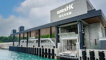 Un bâtiment situé au bord de l’eau, sur lequel on peut lire l’inscription « WESTK » ainsi que des caractères chinois. Il est doté d’une passerelle couverte et d’une jetée qui s’avance dans l’eau.
