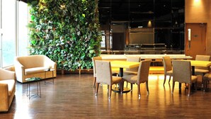 A modern dining area with wooden flooring, beige upholstered chairs, and a large green vertical garden wall. - Dorsett Mongkok, Hong Kong (Kowloon)