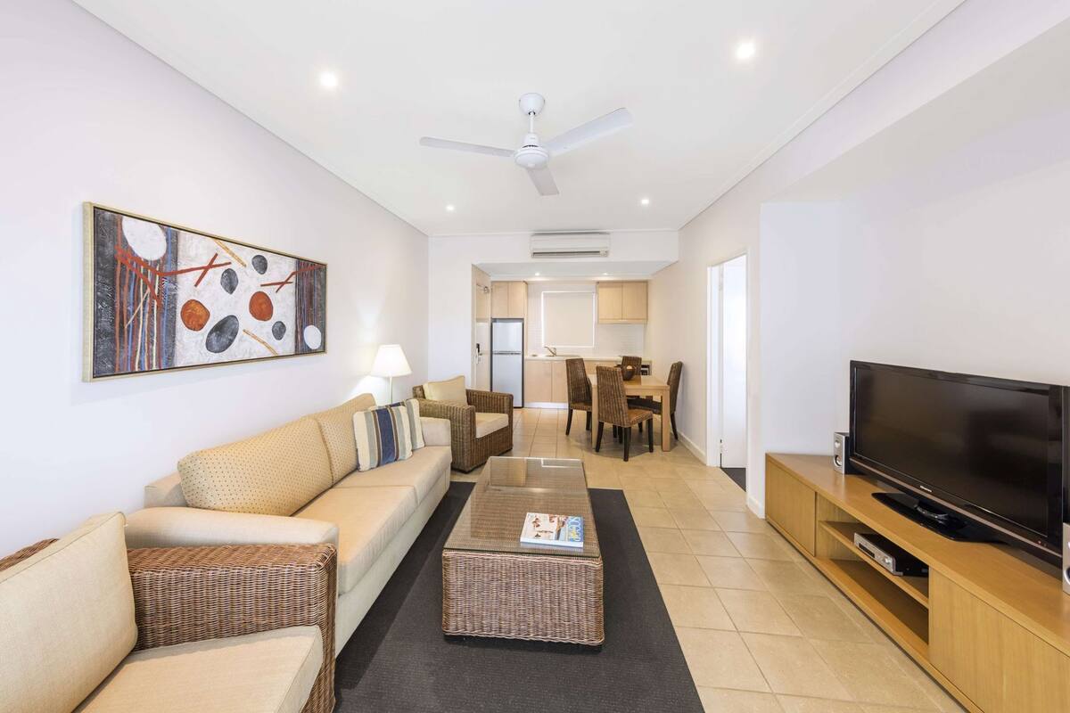 A living room with a sofa, coffee table, TV, and artwork on the wall.