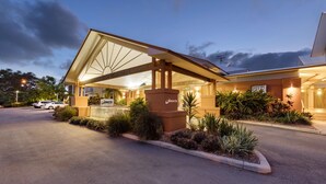 A hotel entrance with a covered outdoor area, a sign, and a parking lot. - Oaks Broome Hotel (Broome)