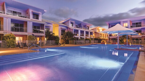 A modern hotel with a swimming pool, balconies, and a well-lit facade. - Oaks Broome Hotel (Broome)