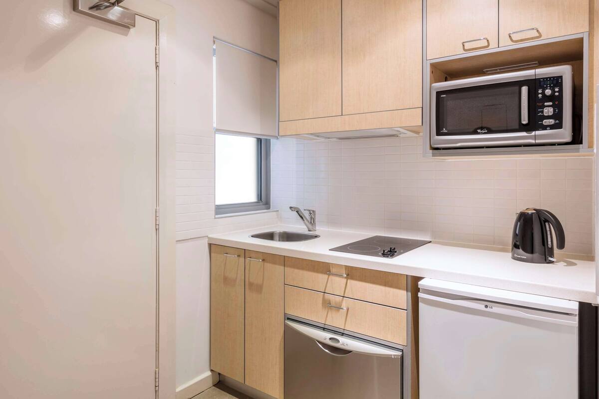 A compact kitchen with a microwave, sink, and dishwasher.