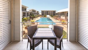 A balcony with a view of a swimming pool, wicker furniture, and a tiled floor. - Oaks Broome Hotel (Broome)