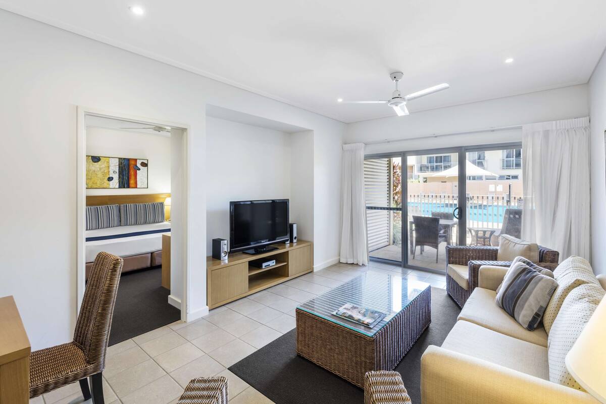 A modern living room with a television, sofa, and wicker furniture.