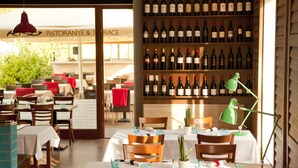 A restaurant interior with tables set for dining, a wine rack with numerous bottles, and a view of the outside restaurant area. - Hotel Castle Garden (Budapest)