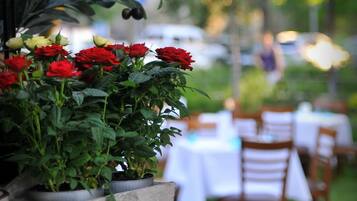 A restaurant with outdoor seating, potted plants, and a sign above the entrance.