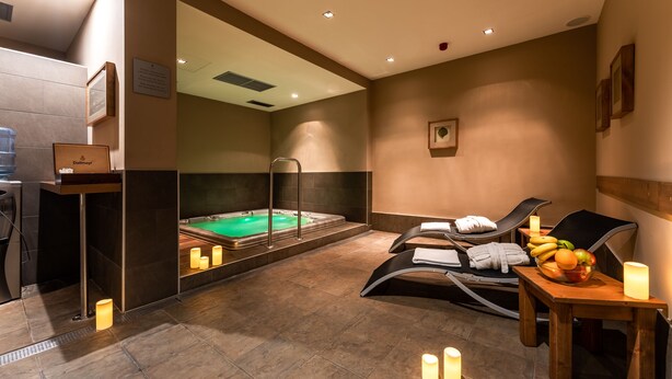 A spa room with a hot tub, massage chairs, and a fruit bowl on a table. - Hotel Castle Garden (Budapest)