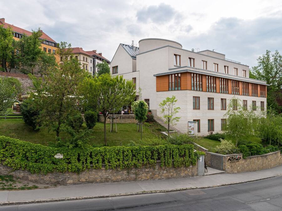 Un edificio moderno con tejado plano, amplios ventanales y una pared de piedra con vegetación.