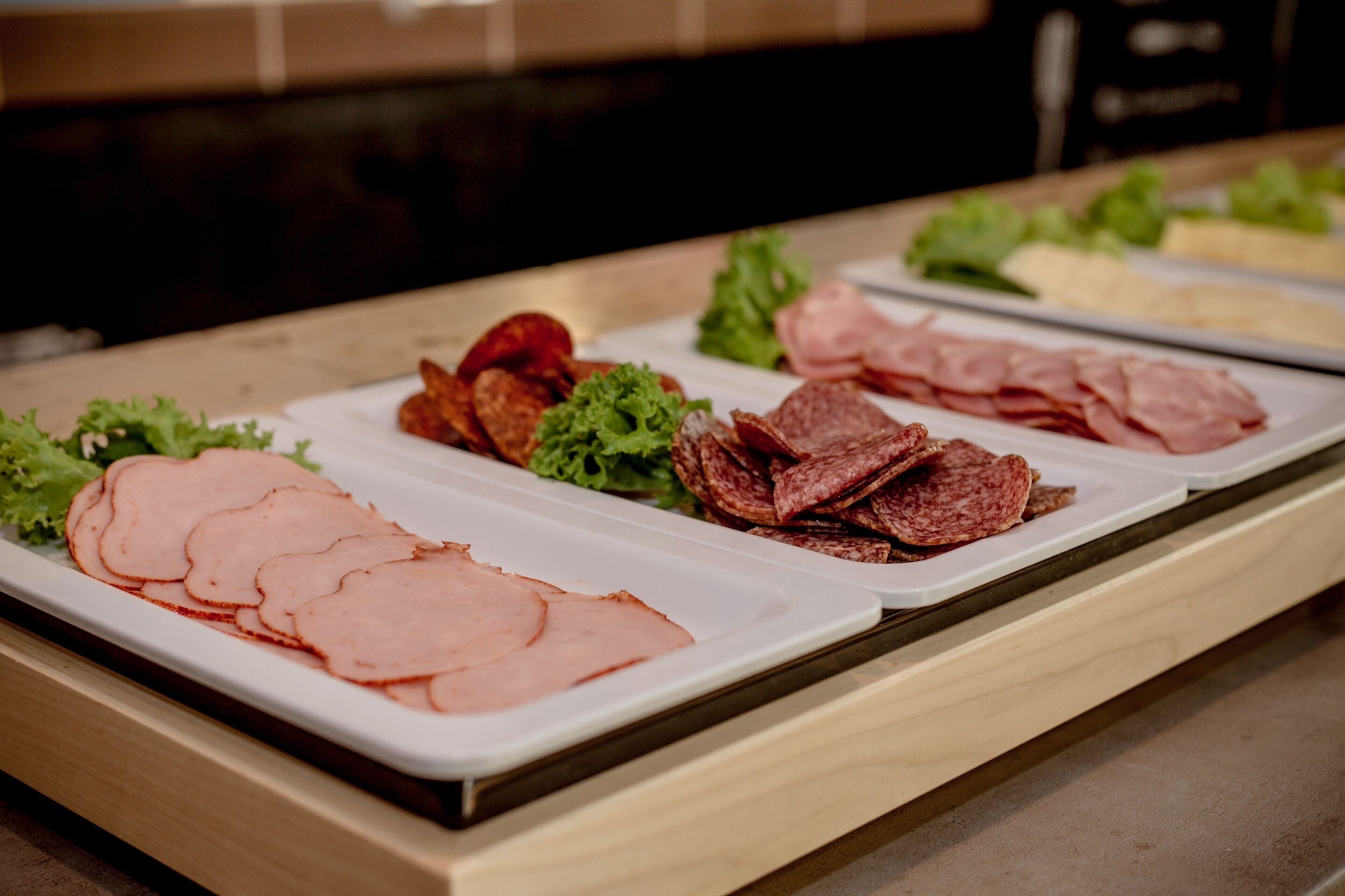 A buffet with various sliced meats and vegetables.