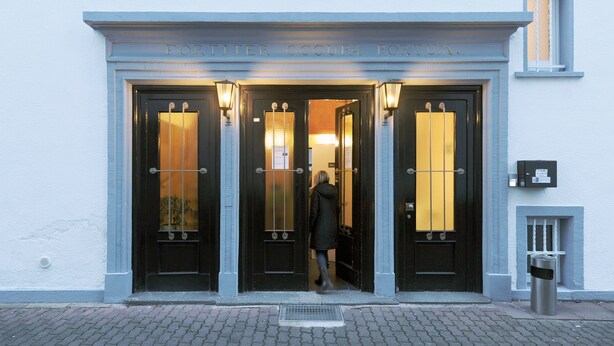 A hotel entrance with a black door and illuminated windows.