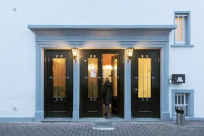 L’entrée d’un hôtel, avec une porte noire et des fenêtres illuminées.