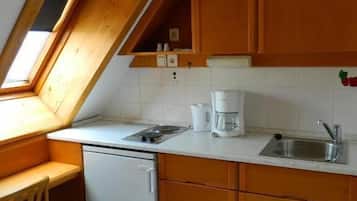 Una cocina con armarios de madera, lavavajillas, pileta y ventana.