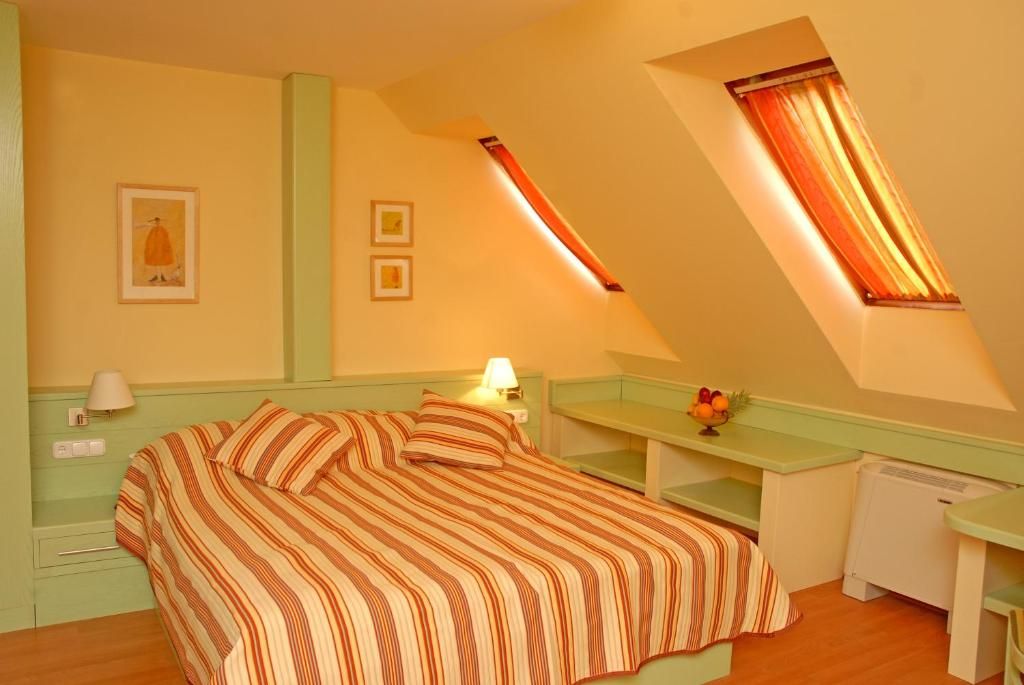Une chambre avec un lit, un bureau, une lampe et une petite table sur laquelle se trouvent des fruits.