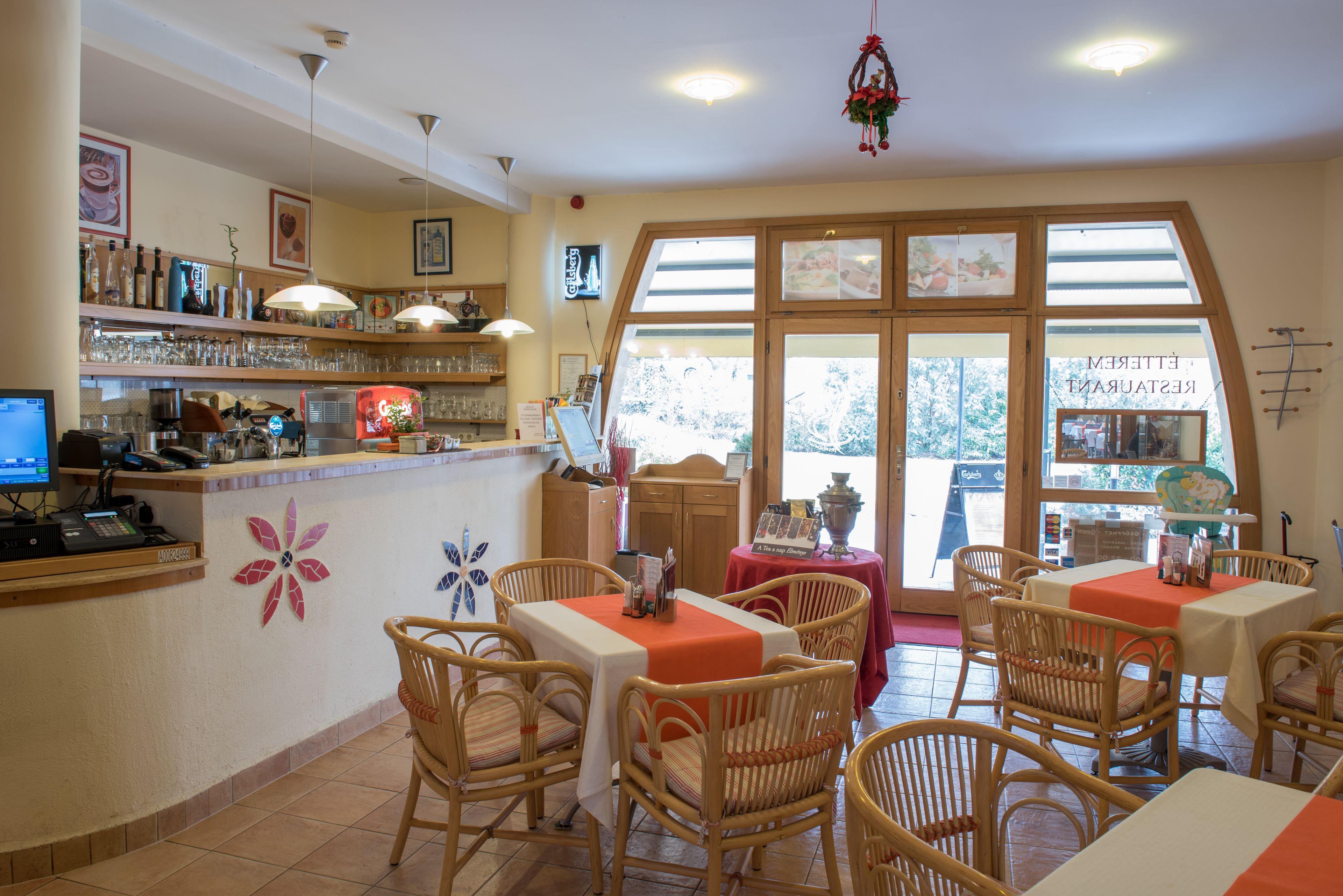 Een restaurantinterieur met een bar, rieten stoelen en een groot raam met uitzicht.