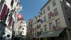 Una calle con edificios mostrando varias banderas, entre ellas la bandera suiza.