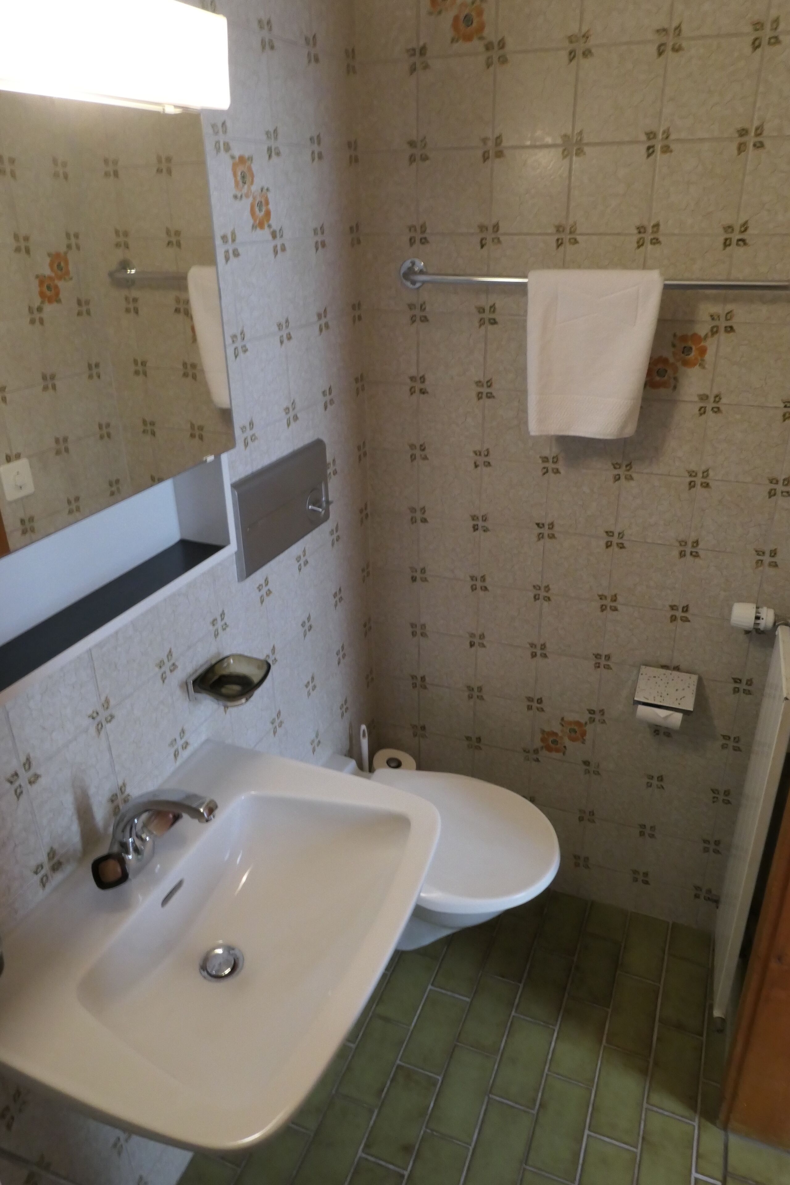 A bathroom with a sink, toilet, and a towel rack.