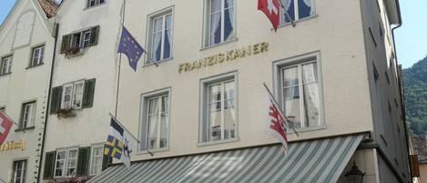 A building with multiple flags, including the European Union flag, and a sign reading "FRANZISKANER".