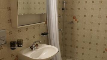 A bathroom with a sink, mirror, shower, and toilet.