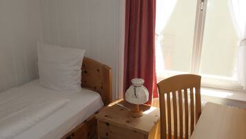 A bedroom with a wooden bed, a bedside table with a lamp, and a chair.