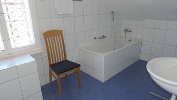 Ein Badezimmer mit Badewanne, Waschbecken und einem Sessel.