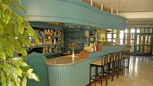 Un espace bar doté d’un comptoir incurvé, de tabourets et d’étagères remplies de bouteilles.