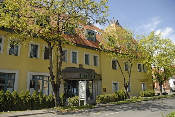 A yellow building with a sign that reads "HOTEL" and a signboard with the name "Club Ararat Hotel".