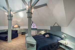 Un dormitorio con cama, escritorio, silla y ventana con diseño de vitral.