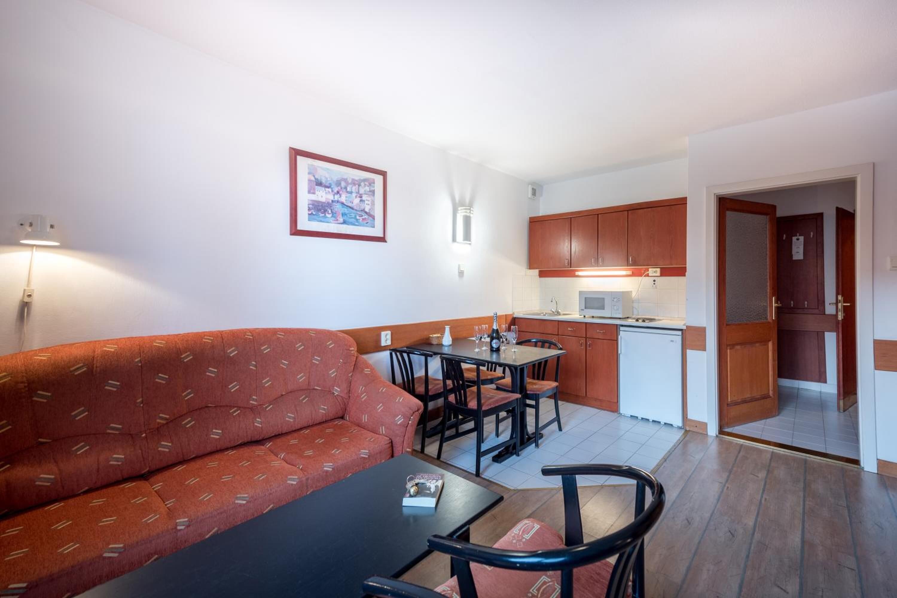 A compact living space with a sofa, dining table, chairs, a kitchenette, and a small kitchen area.
