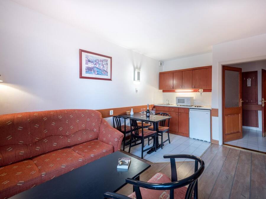 A compact living space with a sofa, dining table, chairs, a kitchenette, and a small kitchen area.