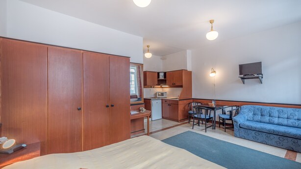Een slaapkamer met een bed, een bank, een bureau en een kitchenette.