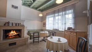 Une pièce chaleureuse avec une cheminée, une table à manger et une fenêtre avec des rideaux.