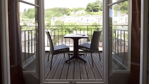A balcony with a table and chairs, offering a view of a residential area. - Le Beausejour (Plombieres-les-Bains)