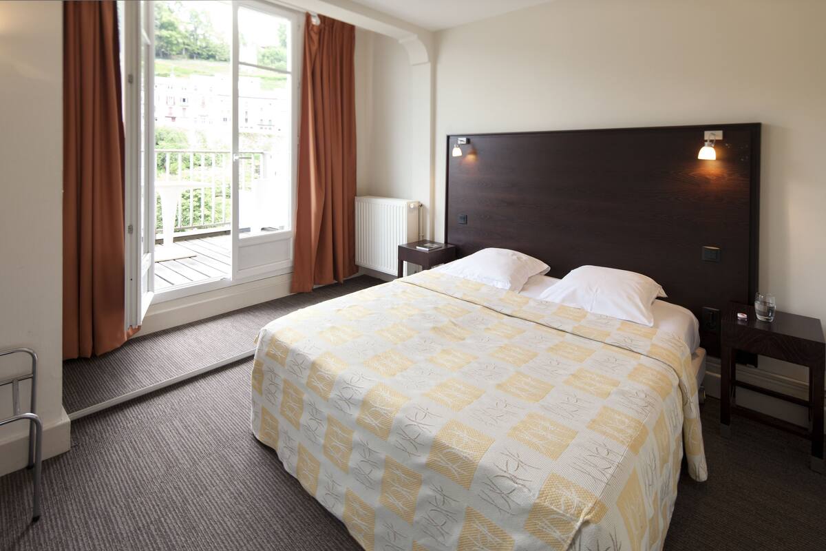Habitación de hotel con una cama grande, una mesita de noche y vistas a zonas verdes.