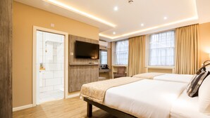 Una camera d'albergo moderna con un letto grande, una TV fissata alla parete e un bagno visibile attraverso una porta aperta.