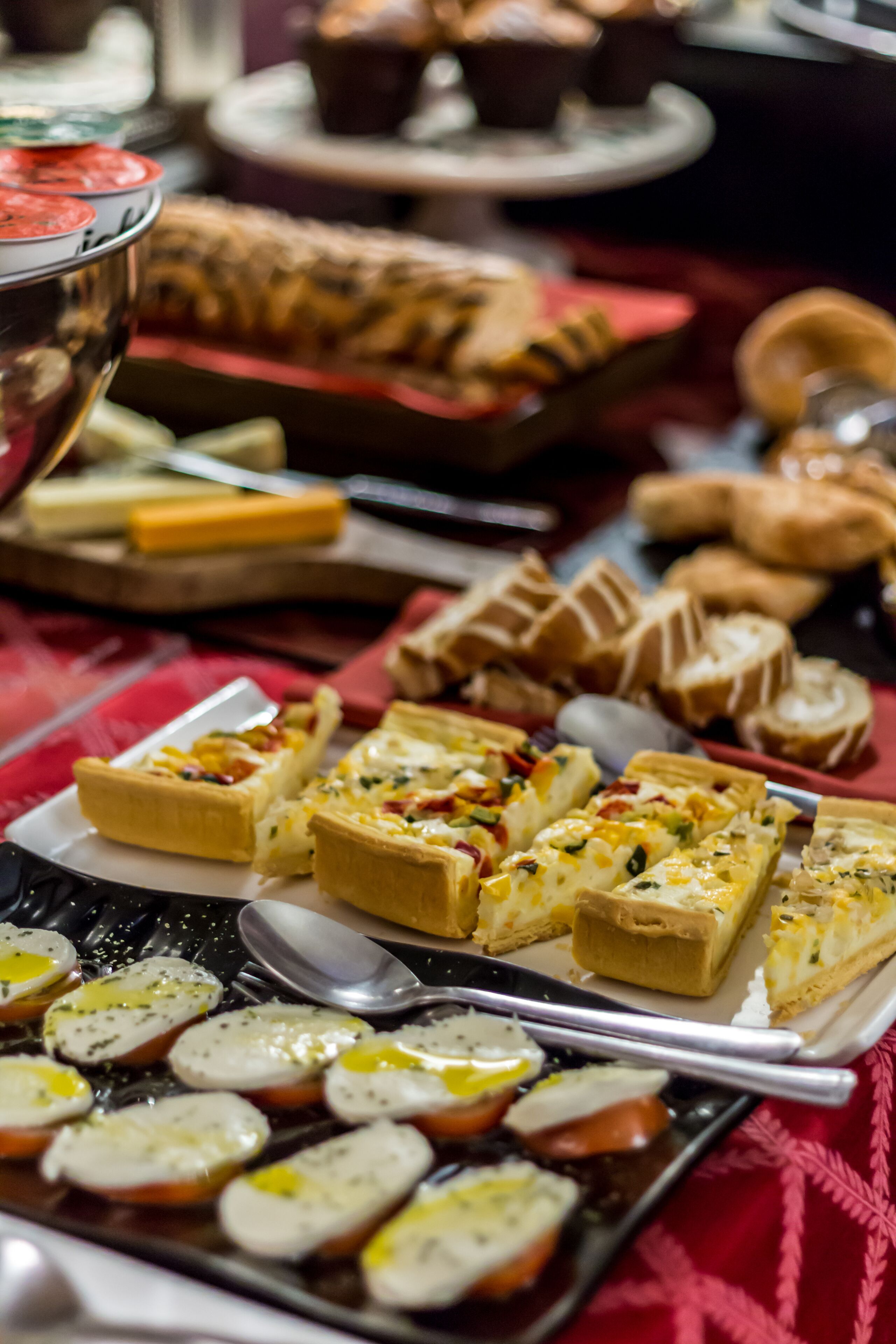 A buffet table with various food items including quiches, pastries, and sliced meats.