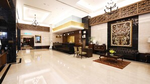 A spacious lobby with a reception desk, seating area, and a large decorative wall.