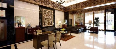 A spacious lobby with a reception desk, seating area, and a large decorative wall piece.