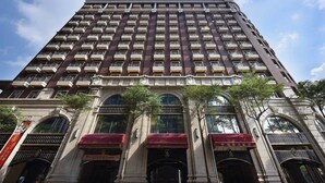 A tall, multi-story building with a symmetrical facade, featuring evenly spaced balconies and large windows.