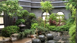 A traditional Japanese garden with a koi pond, stone lanterns, and various plants.