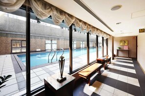 A hotel room with a large window overlooking a swimming pool, a bench, and a trophy on a table. - Fullon Hotel Taoyuan (Taoyuan City)
