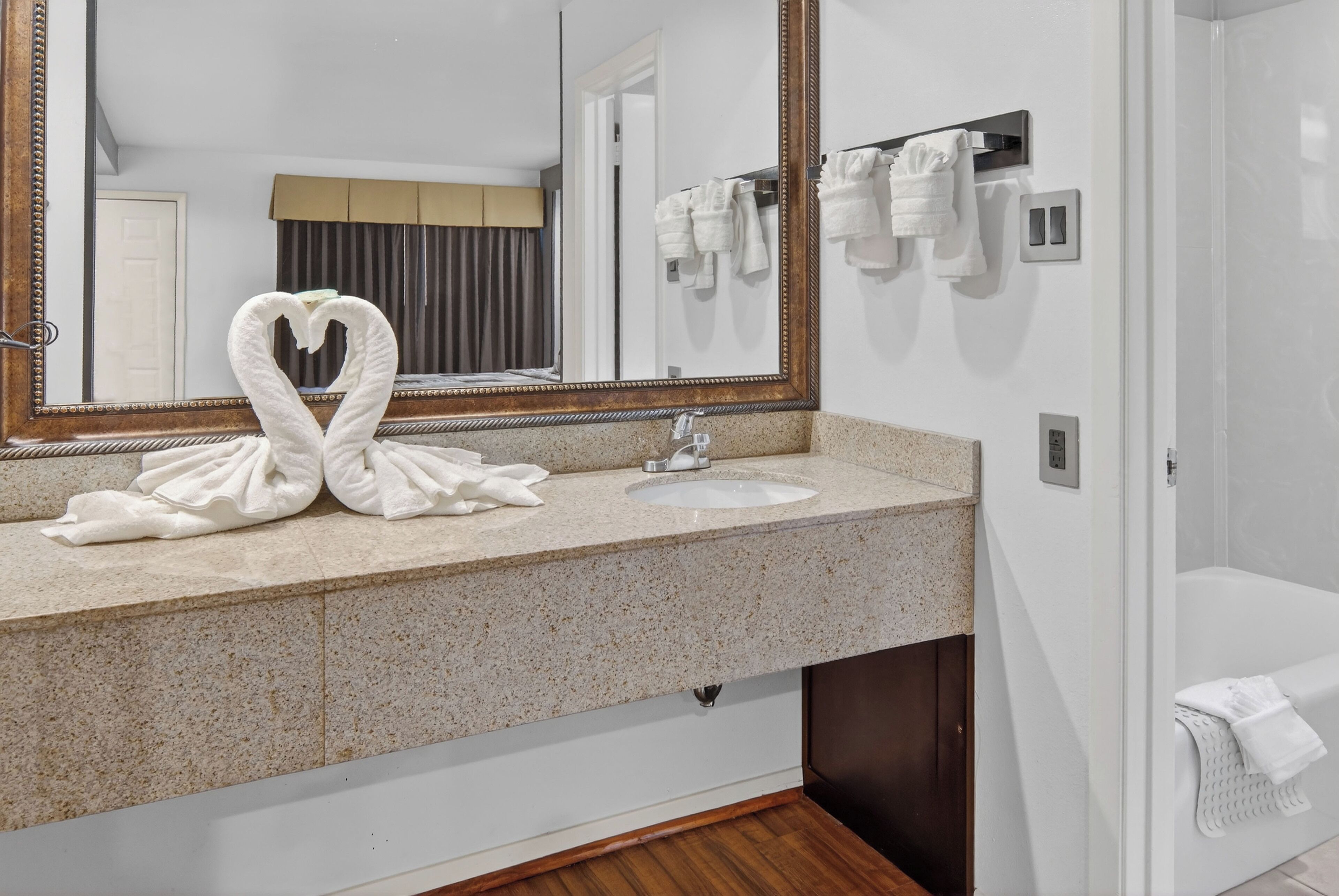 A bathroom with a granite countertop, a sink, a mirror, and a towel rack with towels.