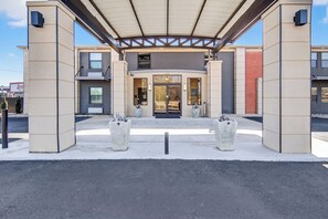 Une entrée moderne, avec un passage couvert, de grandes fenêtres et une porte centrale.