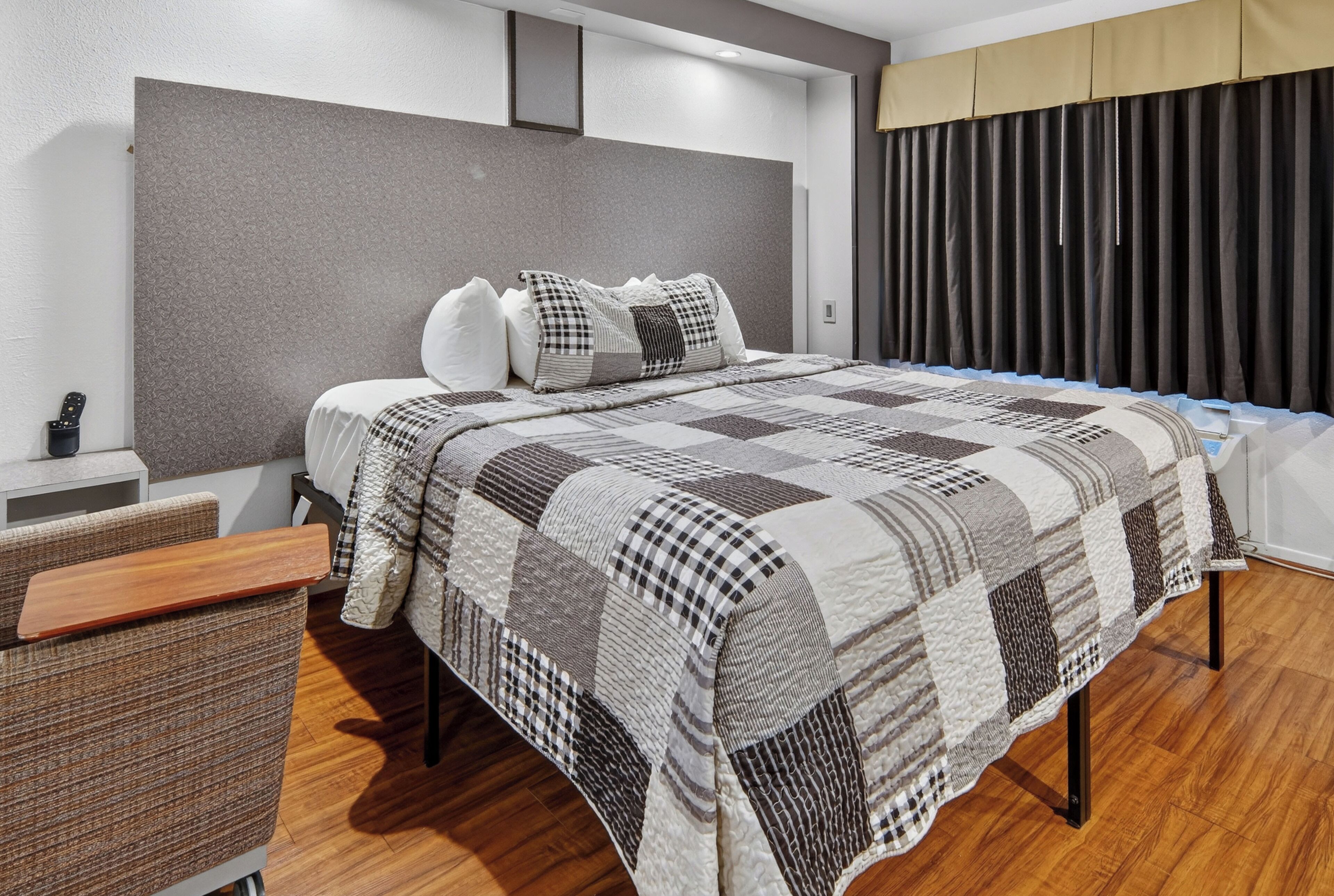 Une chambre à coucher moderne avec un grand lit, une table de chevet, une commode et un banc en bois.