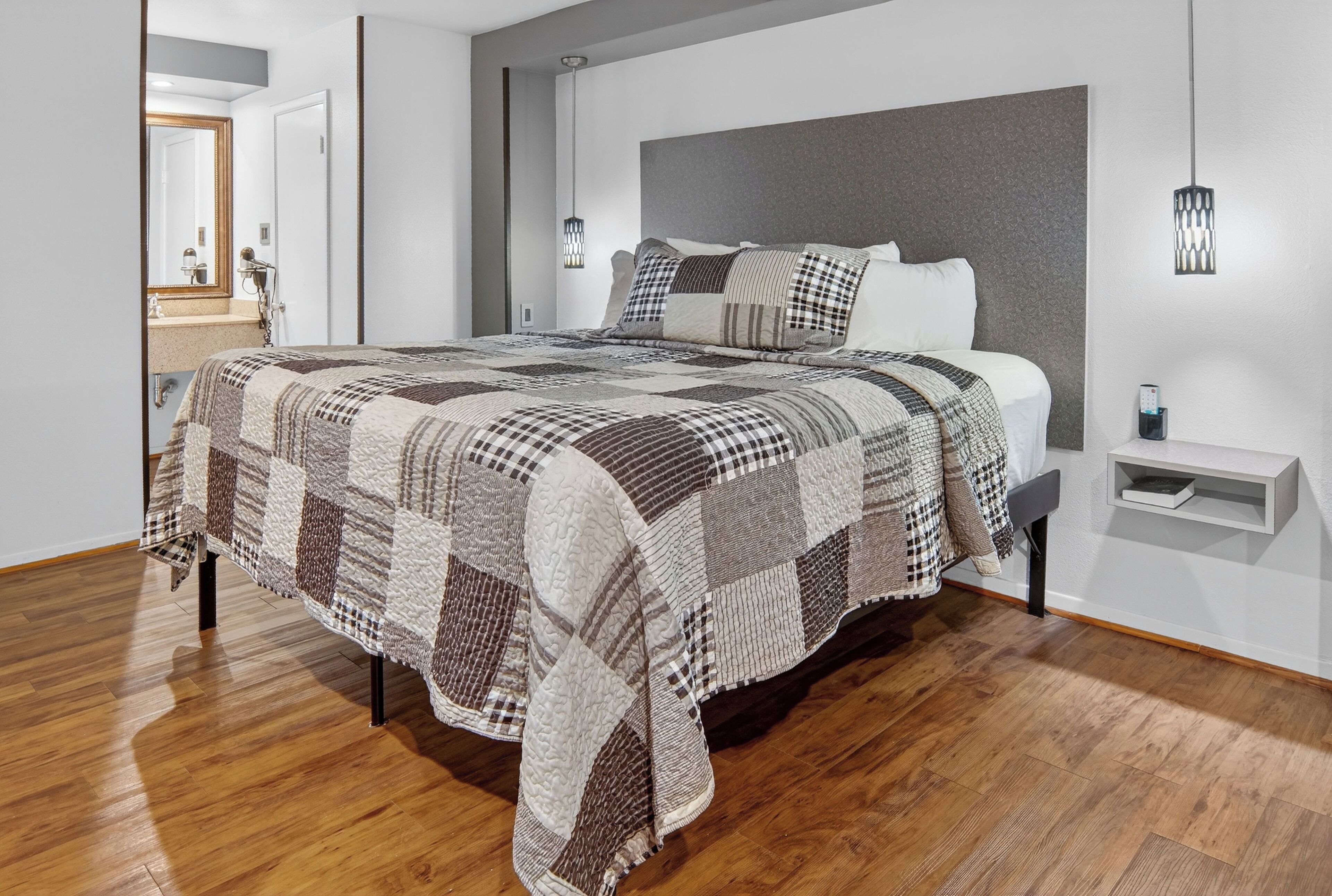 A modern bedroom with a large bed, a bedside table, and a nightstand.