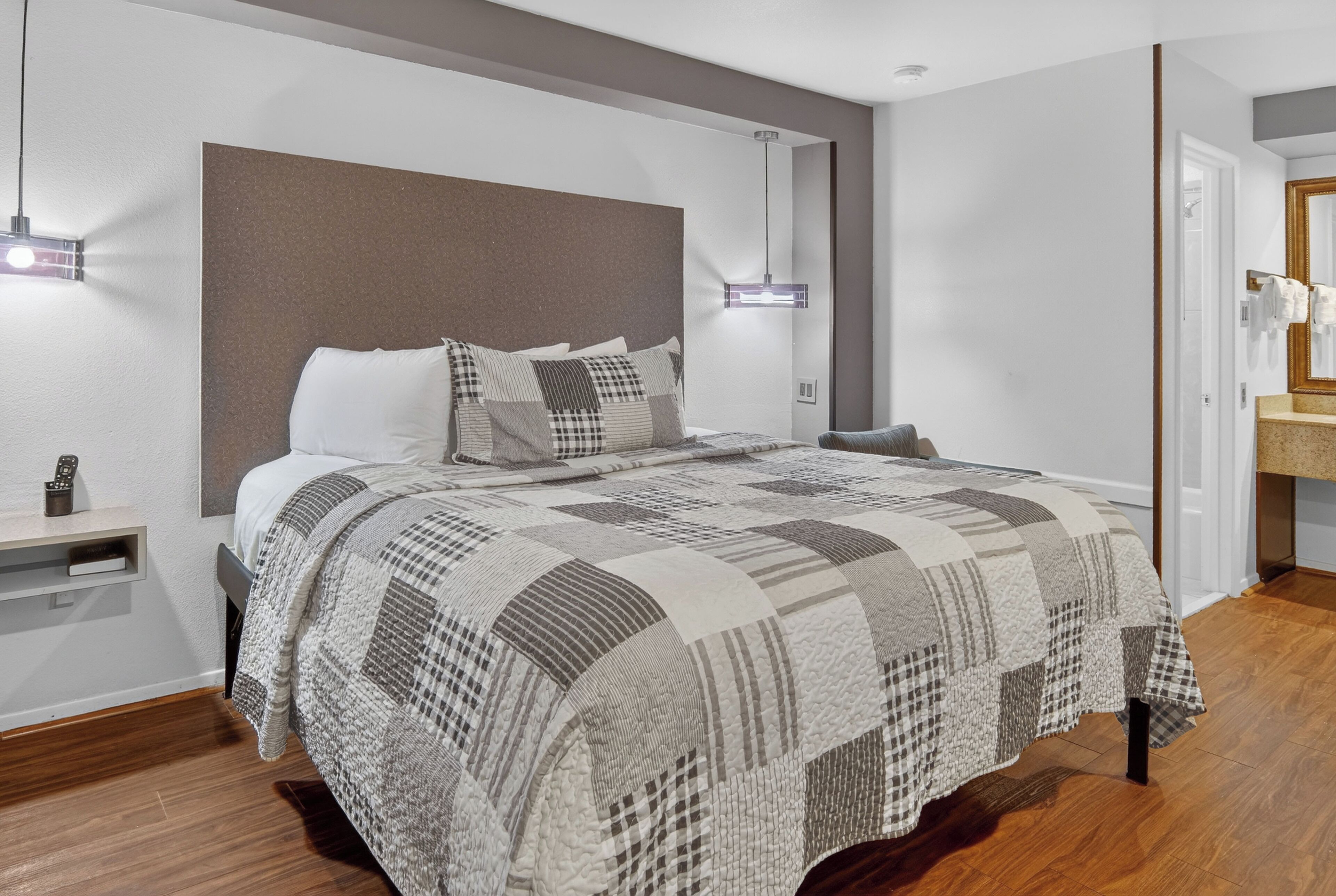 A modern bedroom with a large bed, a headboard, bedside tables, and a nightstand.