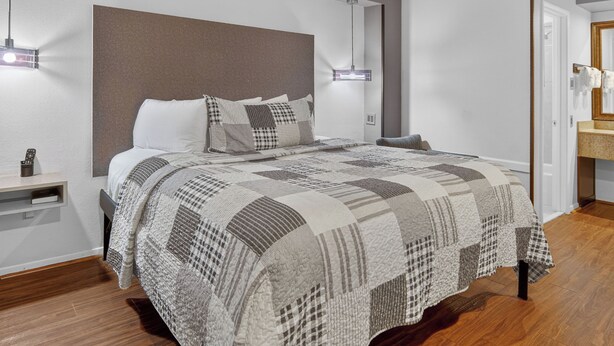 Une chambre à coucher moderne avec un grand lit, une tête de lit, des tables de chevet et une table de nuit.