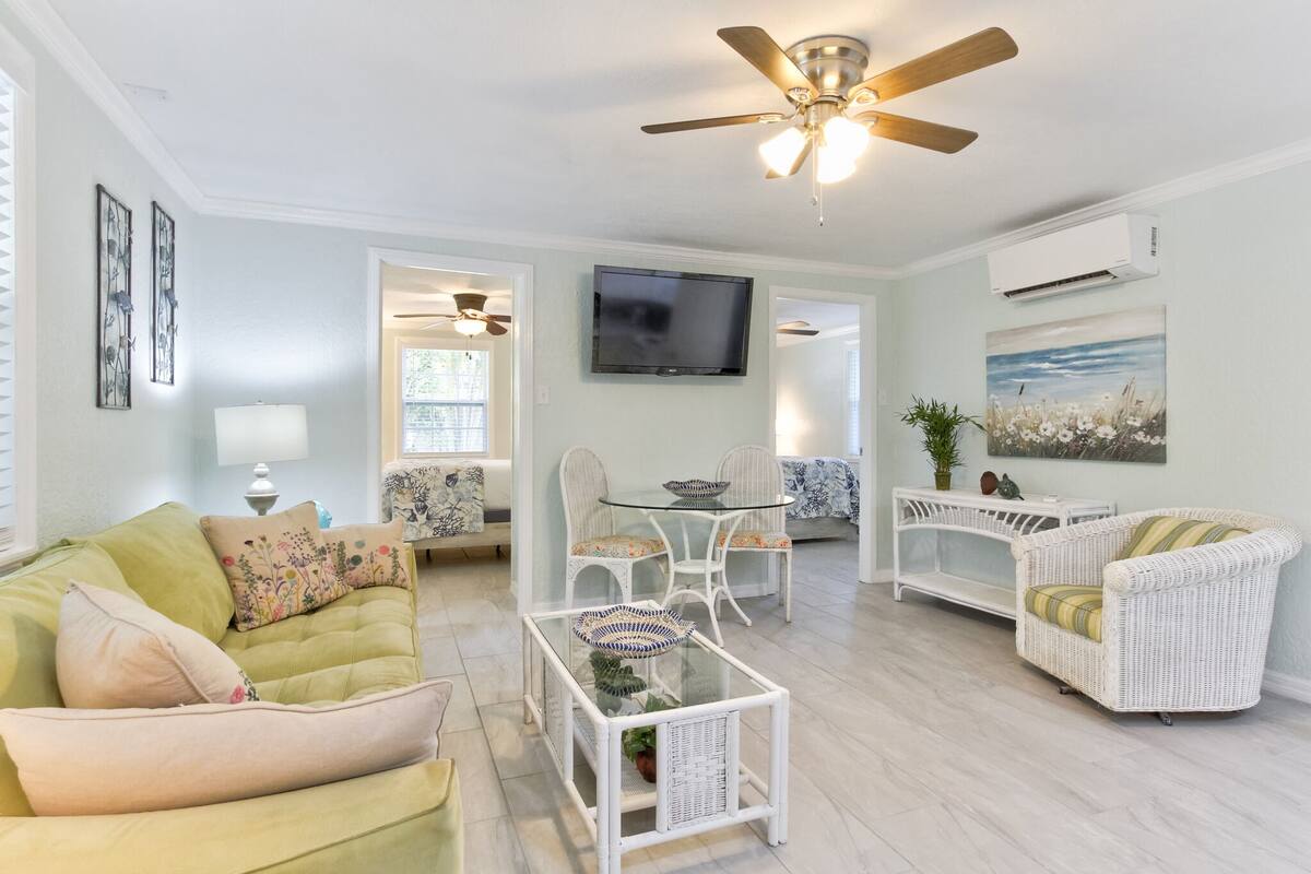 A living room with a sofa, armchairs, a coffee table, a TV, and a ceiling fan.