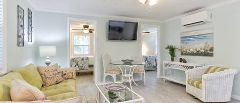 A living room with a sofa, armchairs, a coffee table, a TV, and a ceiling fan.
