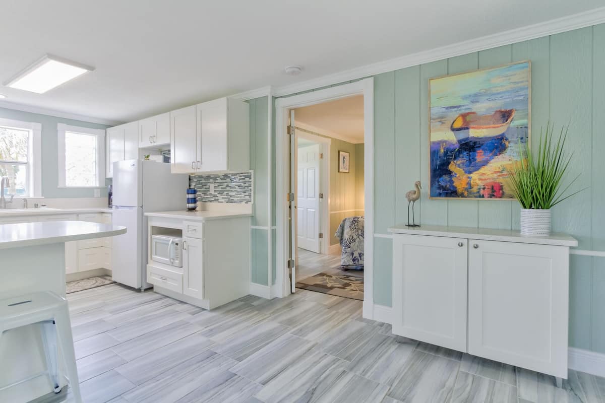 A modern kitchen with white cabinets, a granite countertop, and a large window.