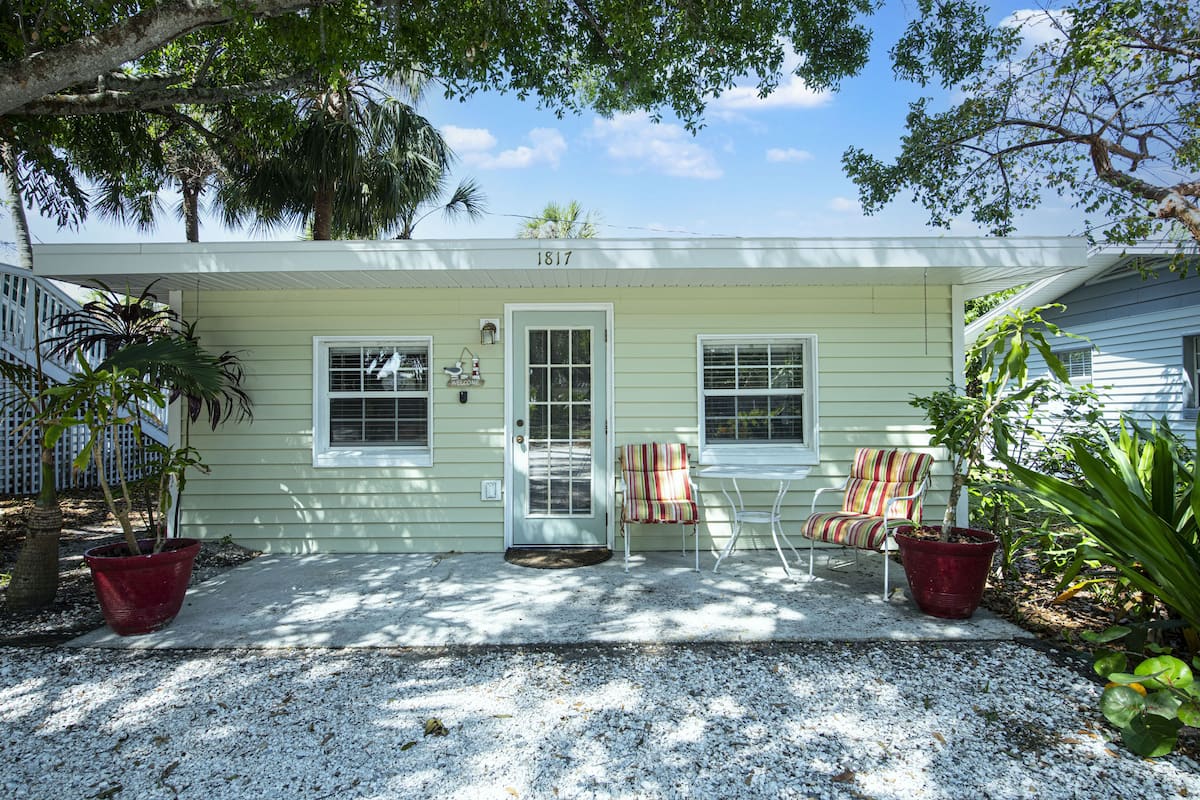 A house with the number 1817 on the front, two chairs, and potted plants.